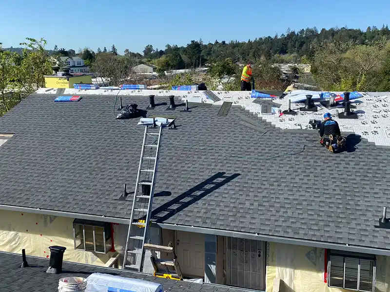 Acme Roofing Services crew installing new gray shingles on a home